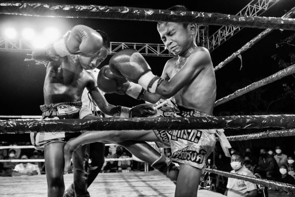 Due bambini si affrontano in un incontro di Muay Thai Kids in Thailandia, fotografia documentaria di Alain Schroeder