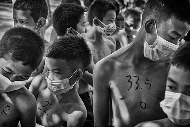 Bambini con numeri scritti sul petto in attesa della pesatura prima di un incontro di Muay Thai Kids, Alain Schroeder