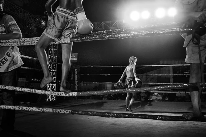 Giovane pugile solo al centro del ring durante un incontro di Muay Thai Kids in Thailandia, foto Alain Schroeder