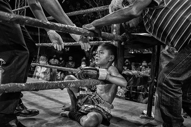 Bambino seduto sul ring dopo un incontro di Muay Thai Kids, fotografia di Alain Schroeder