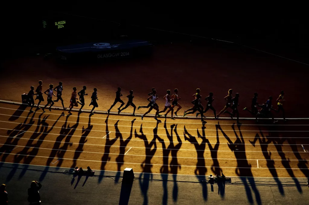Fotografia sportiva di Tom Jenkins a Glasgow 2014 con ombre geometriche dei corridori sulla pista di atletica leggera