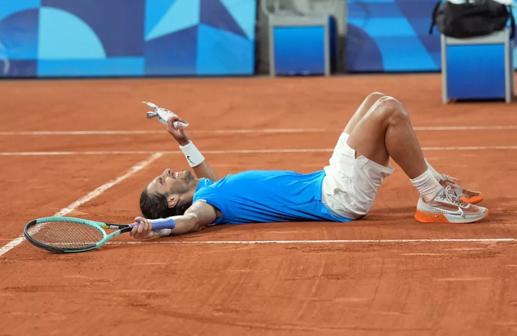 Lorenzo Musetti sdraiato sul campo da tennis