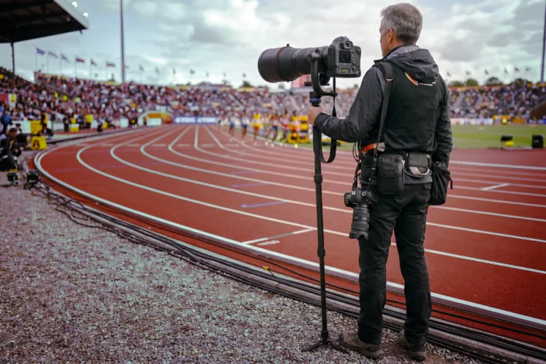Fotografo a bordo pista di atletica con un teleobiettivo zoom