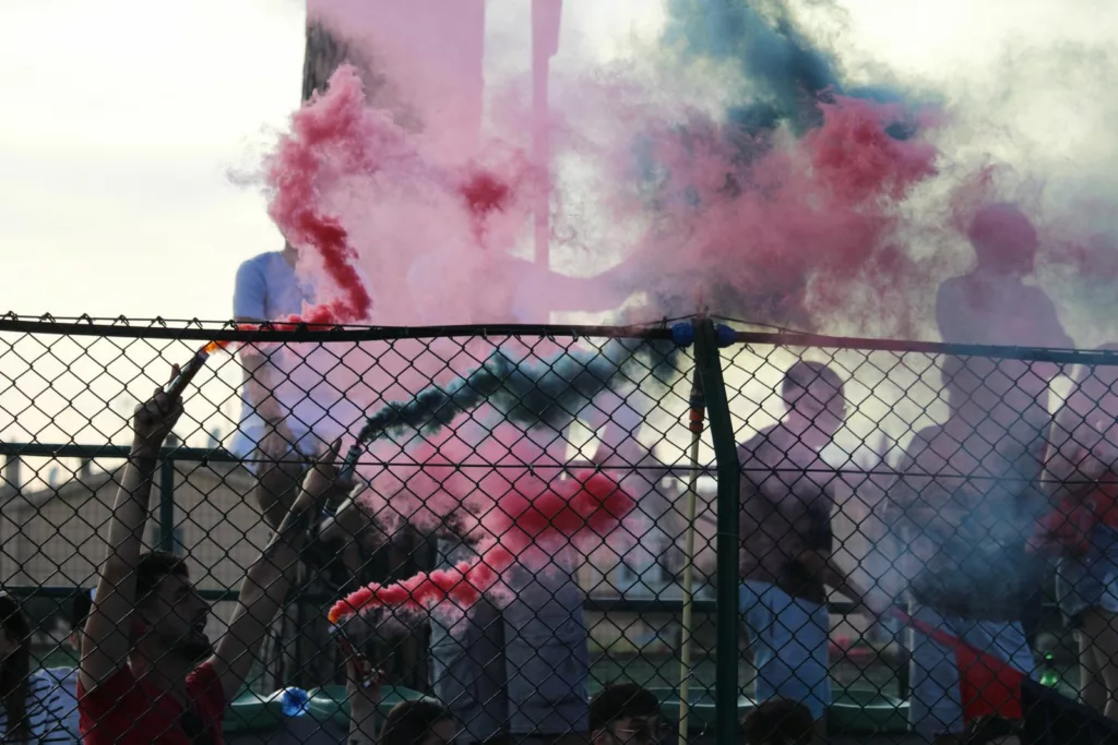 Tifosi dietro una rete metallica con fumo rosa e verde. Sofia Gasbarri — ASD Montorio Romano — SPORTSHOTS Magazine