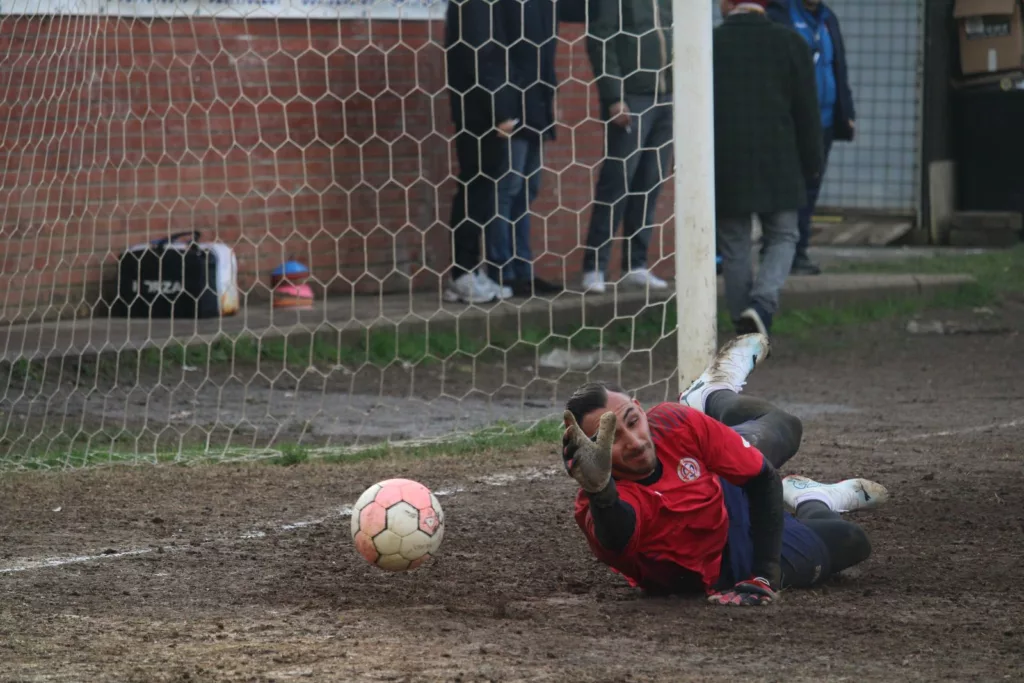 Portiere in maglia rossa a terra accanto alla porta, pallone vicino alla rete. Sofia Gasbarri — ASD Montorio Romano — SPORTSHOTS Magazine
