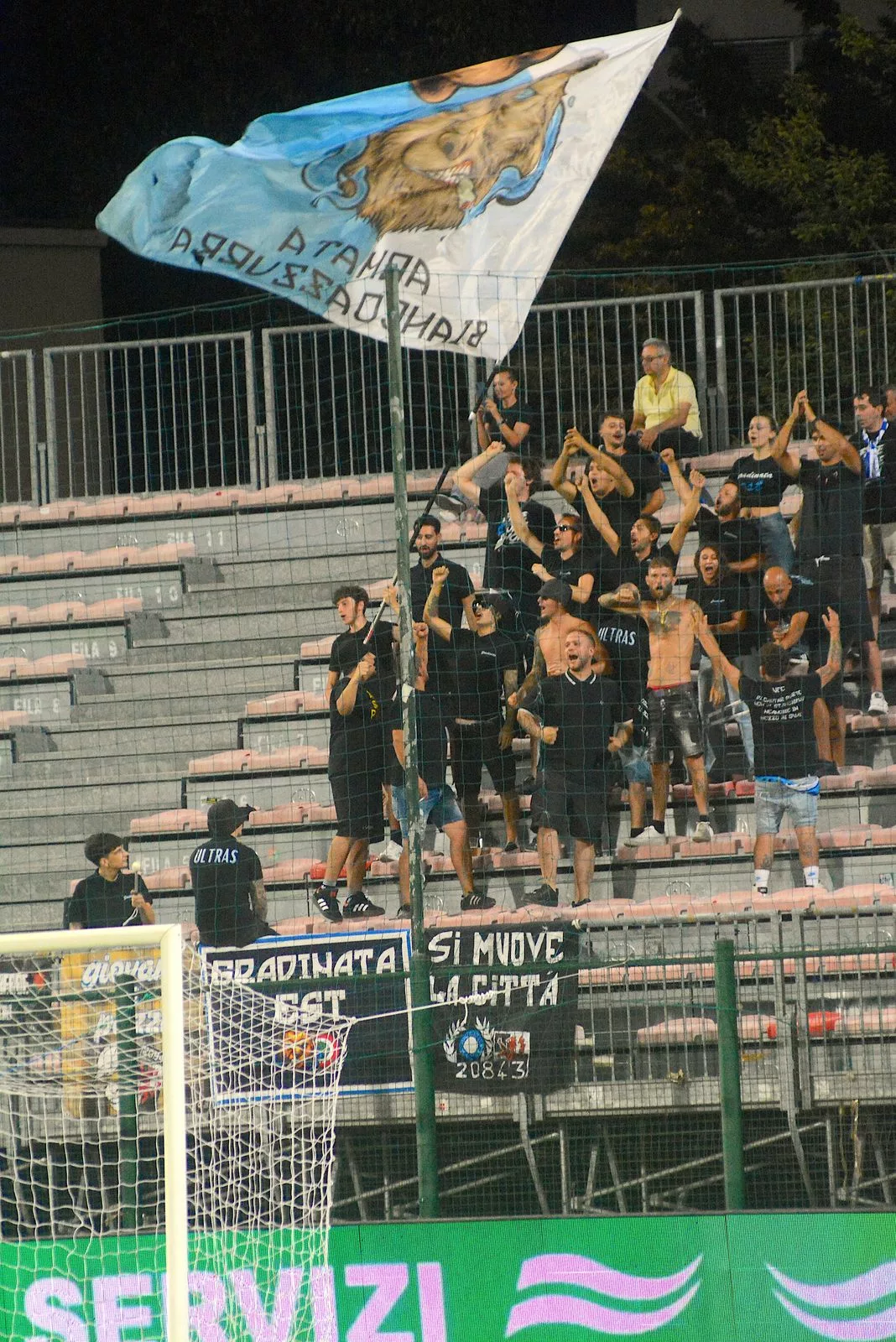 Tifosi in gradinata con una bandiera biancazzurra allo stadio di Gorgonzola.
